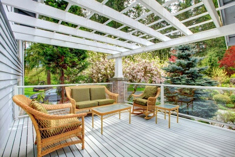 Timber deck with an attached pergola and rattan sofa facing the garden