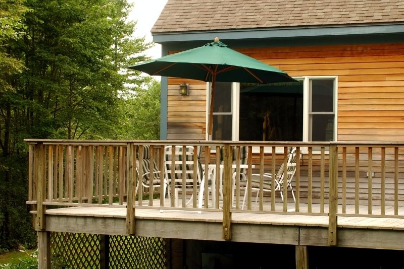 Timber deck with railing, patio table and umbrella outside a home