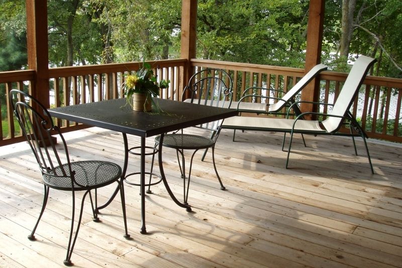 Covered timber patio deck with an outdoor dining table, chairs and lake views