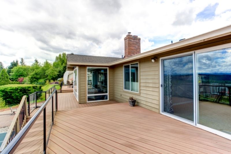 Wide timber deck with metal railing wrapping around a house