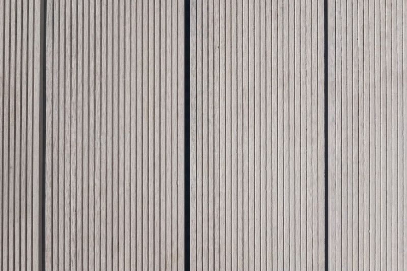 Close-up of grey composite decking boards showing the wood-grain finish